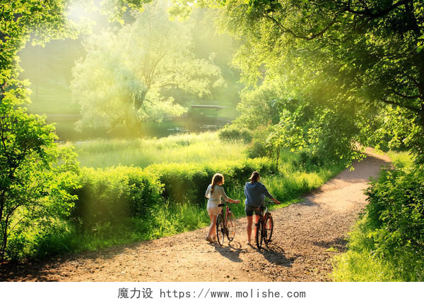 绿色唯美自然阳光投射的森林一男一女情侣两个人推自行车人物风景图片